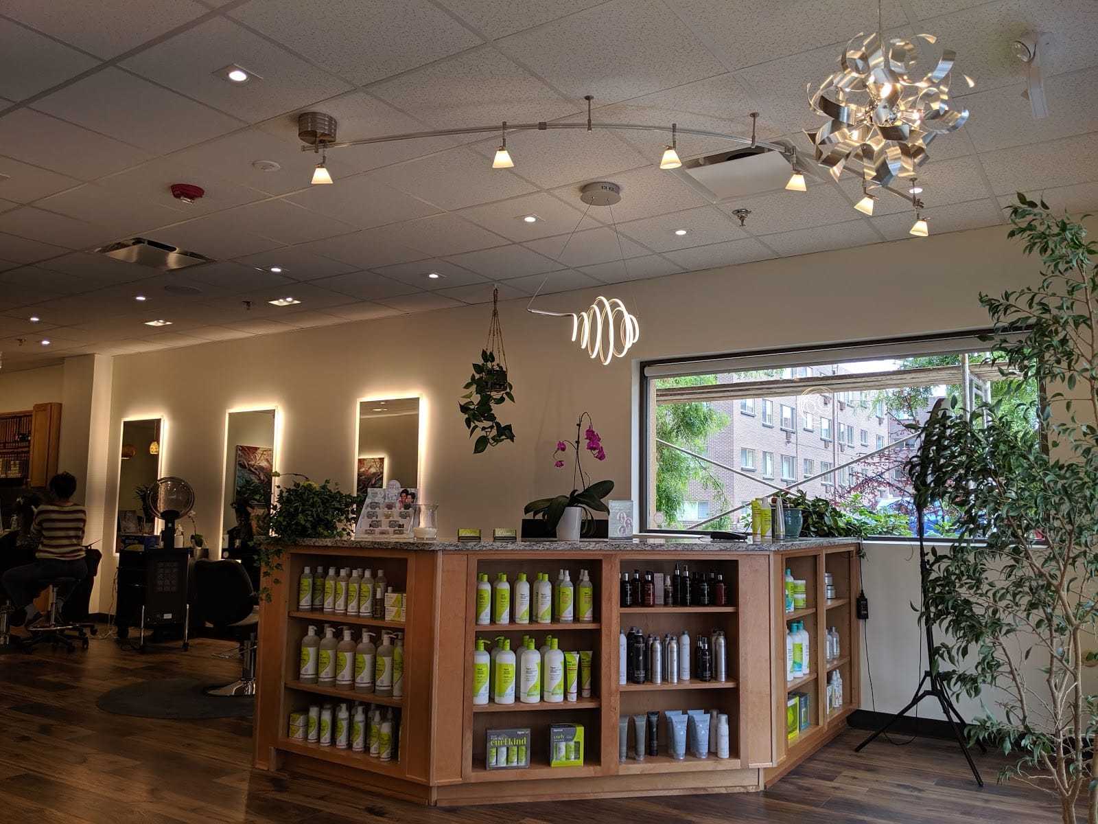 Modern hair salon interior with product display, large window, and stylish lighting fixtures.